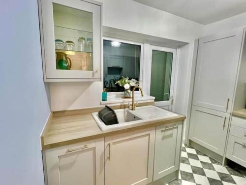 a white kitchen with a sink and a checkered floor at Betty's Bungalow in Lancing