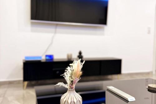 a white vase with flowers in front of a tv at Royal Stay in Olsberg