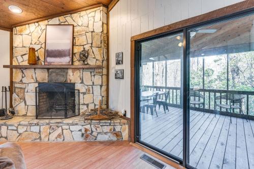 a living room with a stone fireplace and a deck at Smoky Mountain Cabin with Fire Pit and Stunning Views! in Andrews