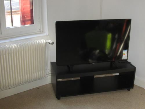 - une télévision à écran plat sur un support noir à côté d'une fenêtre dans l'établissement Santy., à Bron