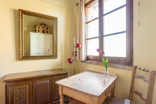 a table with a mirror and a vase with flowers on it at Cozy room at Podere Noceto in Grotti