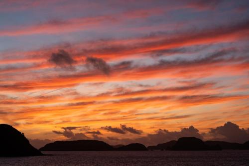 a sunset over the ocean with mountains in the background at サンメール座間味 in Zamami