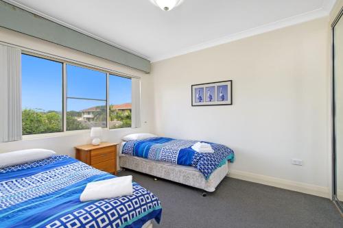 ein Schlafzimmer mit zwei Betten und einem Fenster in der Unterkunft Harbourwatch 11 18 Burrawan Street in Port Macquarie
