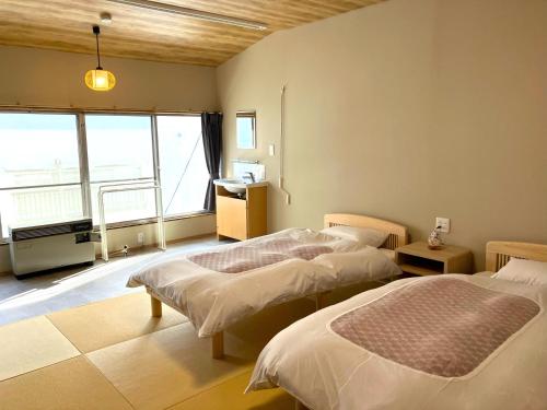 1 dormitorio con 2 camas y ventana grande en Takasagoya Ryokan en Zao Onsen