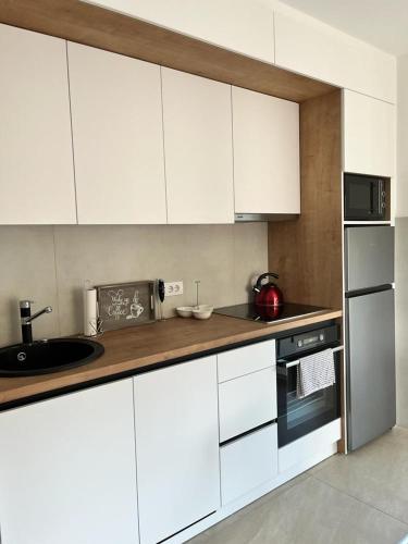 a kitchen with white cabinets and a counter top at LadyDi apartman in Banja Koviljača
