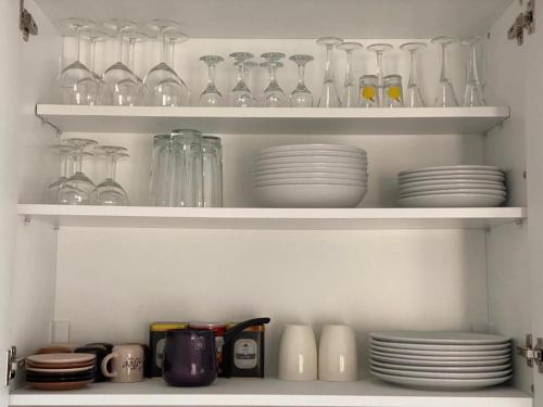 a shelf filled with glasses and plates and bowls at LadyDi apartman in Banja Koviljača