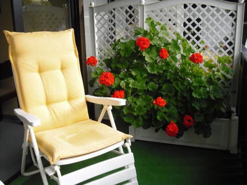 a chair sitting on a porch with red flowers at Gästehaus Cramer in Bad Kissingen