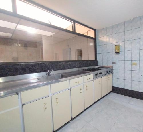 - une cuisine avec un évier et un grand miroir dans l'établissement Innovar Casa Hostal, à Bogotá