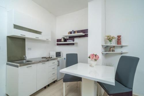 a kitchen with white cabinets and a white table and chairs at Isaura Apartments in Dubrovnik
