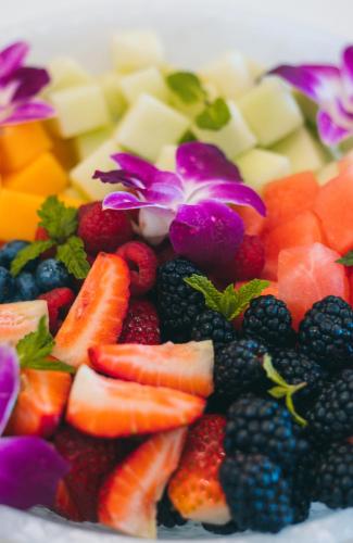 a plate of fruits and vegetables with purple flowers at Black Urchin Boutique Resort in Belford Estates