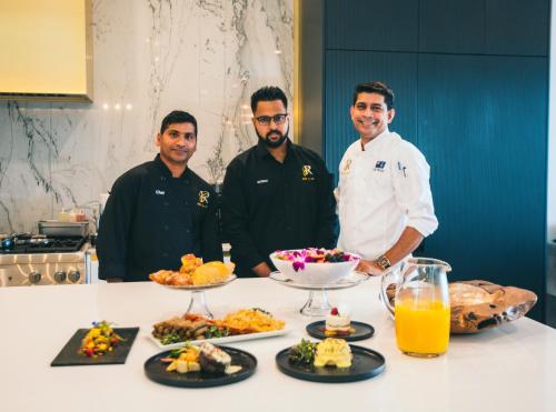 three men standing in a kitchen with food on a table at Black Urchin Boutique Resort in Belford Estates