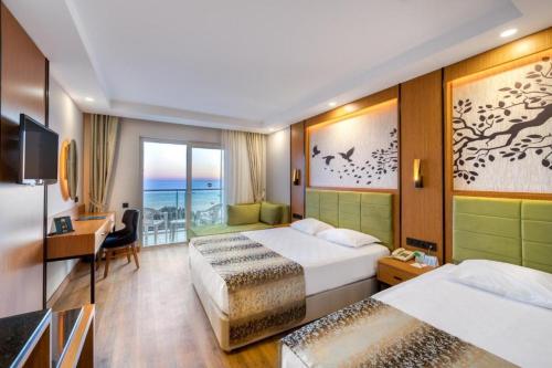 a hotel room with two beds and a desk at Sealife Buket Resort & Spa Hôtel 5 étoiles in Antalya
