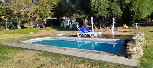 a swimming pool with two blue chairs and a table at Encuentro de Almas (Soulmate Encounter) in Tinogasta