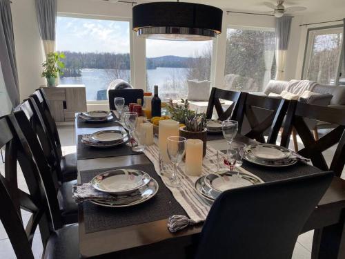 una mesa de comedor con platos y copas de vino en Private Waterfront SPA Perfect Sunsets Lake, en Nominingue