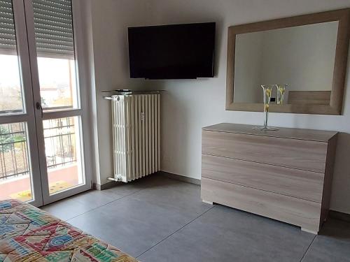 a bedroom with a dresser with a tv and a dresser with a mirror at Sesto Piano Apartment in Asti