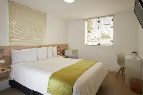 Un dormitorio con una gran cama blanca y una ventana en Natura Inn Hotel en Arequipa