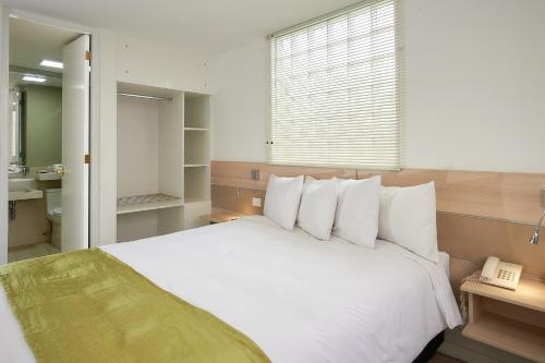 a bedroom with a white bed and a telephone at Natura Inn Hotel in Arequipa