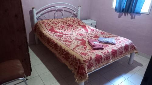 Bett mit einer roten Bettdecke, einer Handtasche und einer Brieftasche in der Unterkunft Lo de la Lu in Gualeguaychú