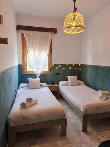 a bedroom with two beds and a chandelier at La Flor De La Xara in Alájar