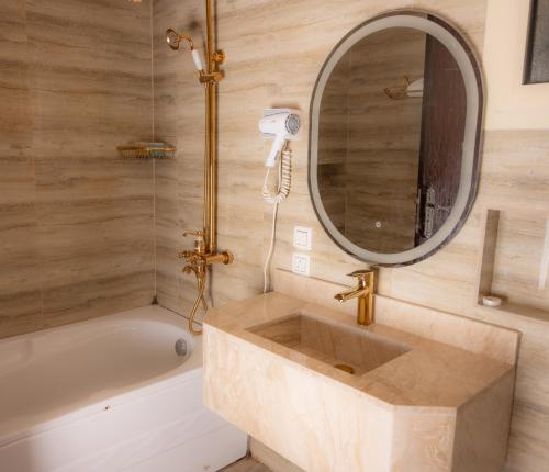 a bathroom with a sink and a tub and a mirror at Areen Hotel in Jeddah