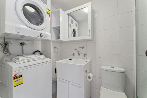 a white bathroom with a sink and a washing machine at Alpine Mountain View 39 Ground Floor 3 Bedroom Unit in Jindabyne