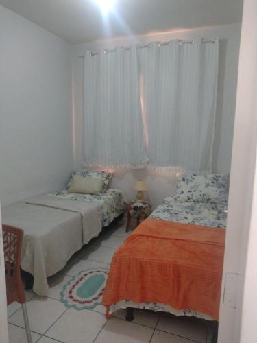 a bedroom with two beds and a window at Apartamento com AR Condicionado, Condomínio aconchegante com piscina 2 Qts in Serra