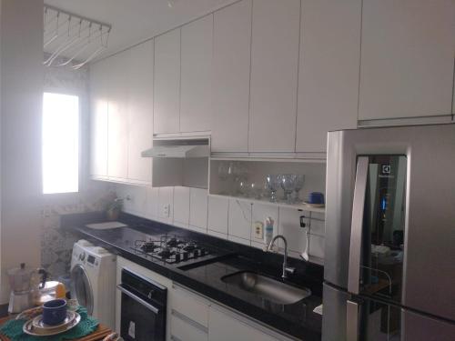 a kitchen with white cabinets and a black counter top at Apartamento com AR Condicionado, Condomínio aconchegante com piscina 2 Qts in Serra