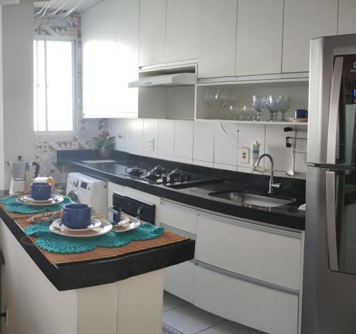 a kitchen with white cabinets and blue dishes on a counter at Apartamento com AR Condicionado, Condomínio aconchegante com piscina 2 Qts in Serra