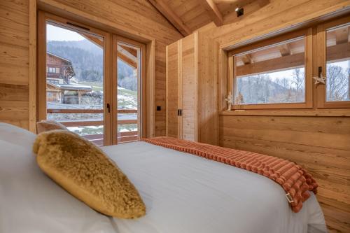 a bedroom with a bed in a wooden room with windows at Chalet Prestige Hélios 12 guests in Megève