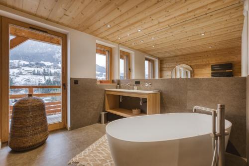 a bathroom with a tub and a sink and a window at Chalet Prestige Hélios 12 guests in Megève