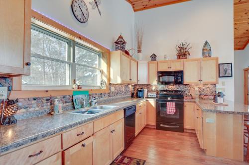 a kitchen with wooden cabinets and a clock on the wall at Lakefront Tomahawk Getaway with Deck and 2 Fireplaces! in Tomahawk
