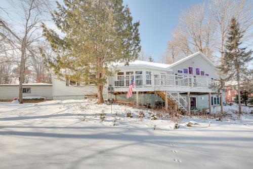 a white house with a porch on a snow covered yard at Lakefront Tomahawk Getaway with Deck and 2 Fireplaces! in Tomahawk