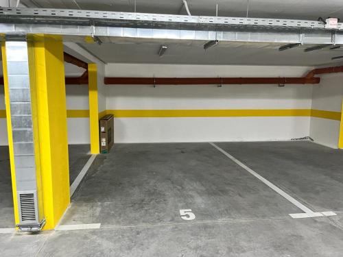 a garage with yellow and white walls and a parking lot at LadyDi apartman in Banja Koviljača