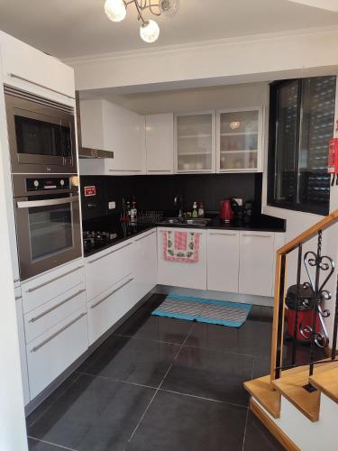 a kitchen with white cabinets and black counter tops at Delfina`s House in Machico