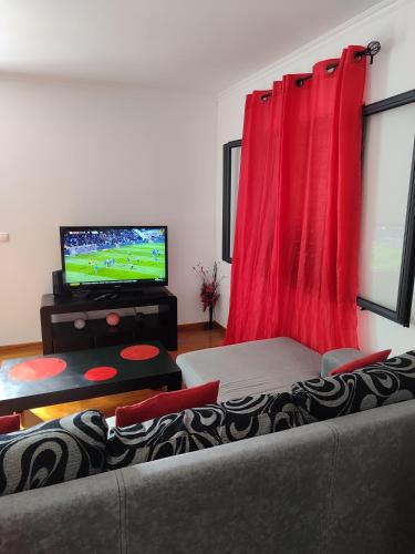 a living room with a couch and a flat screen tv at Delfina`s House in Machico