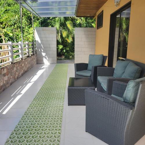 a patio with wicker chairs and a green rug at Villas Playa Palo Seco in Parrita