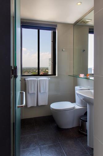 a bathroom with a toilet and a sink and a window at Azumi Boutique Hotel in Manila