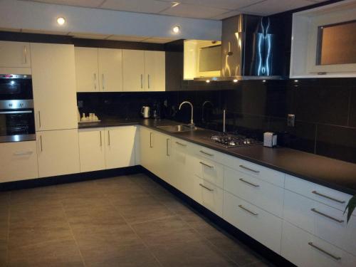 a kitchen with white cabinets and a black counter top at Bed & Kitchen Den Oever in Den Oever