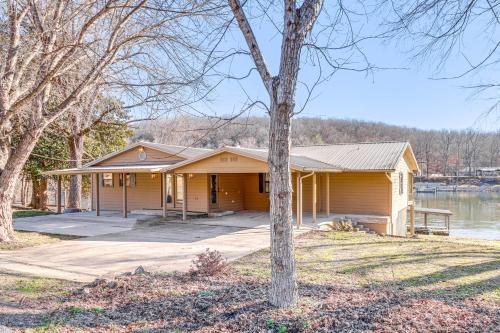 a yellow house with a tree in front of it at Spacious Cabin with Private Dock on White River! in Flippin