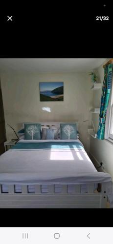 1 dormitorio con 1 cama blanca grande con almohadas azules en Homestay, Upmarket, Wimbledon & Southfields; beside tube; (20 mins to centre) walk to Tennis :, en Londres