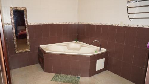 y baño con bañera y azulejos marrones. en Residencial El Amanecer, en Panamá