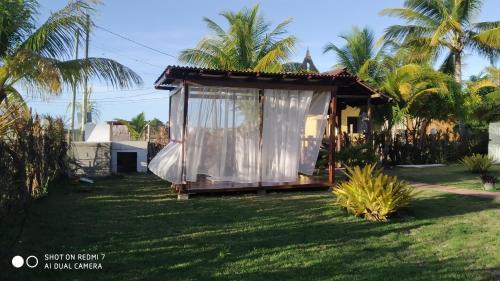 a small house with a white curtain on the yard at Pousada Thai Bungalows-Taipu de Fora in Barra Grande