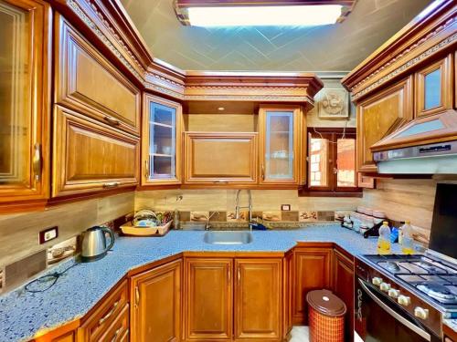 a kitchen with wooden cabinets and a sink at Luxury 5 star apartment with rooftop, security in Maḩallat al Burj