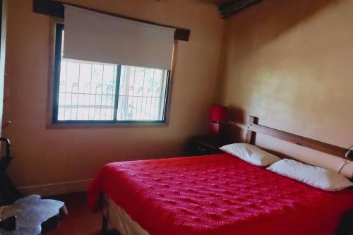 a bedroom with a red bed with a window at Cabaña La tortuga in Siguatepeque