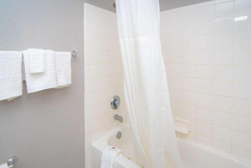 uma casa de banho com uma banheira e um chuveiro com toalhas em Studio 6-West Palm Beach, FL em West Palm Beach