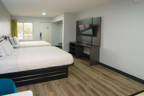 a hotel room with two beds and a flat screen tv at Studio 6-West Palm Beach, FL in West Palm Beach