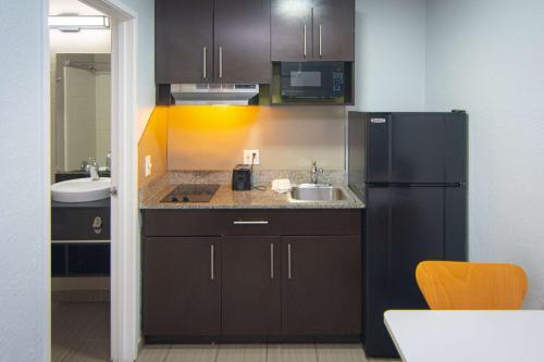a kitchen with a black refrigerator and a sink at Studio 6-Coral Springs, FL - Fort Lauderdale in Coral Springs
