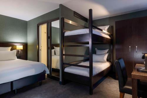 巴黎的住宿－最佳西方布列塔尼蒙帕納斯酒店，酒店客房设有两张双层床和一张书桌。
