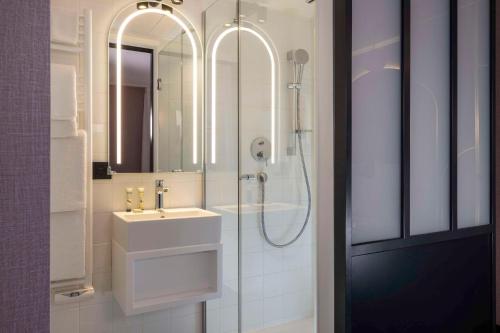 ein Badezimmer mit Waschbecken und Dusche mit Spiegel in der Unterkunft Best Western Bretagne Montparnasse in Paris