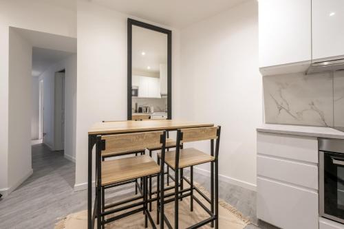 - une cuisine avec un bar avec deux tabourets dans l'établissement Appartement des Colombes - Welkeys, à Courbevoie